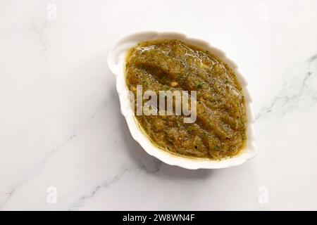 Sauce tomate rôtie maison ou chutney servi dans un petit plat en céramique sur fond blanc avec des ingrédients tomate rôtie, piment vert. Banque D'Images