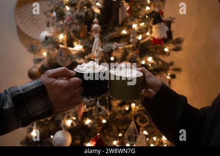Père et fille acclament devant le sapin de noël avec des boissons Banque D'Images