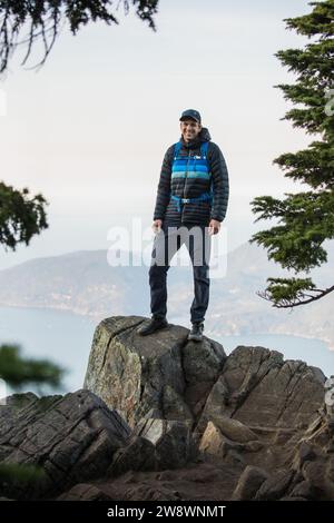 Portrait de randonneur heureux debout sur le sommet rocheux de la montagne, Banque D'Images