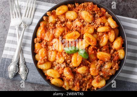 Gnocchi de pommes de terre italiennes cuits avec de la sauce bolognaise à la viande en gros plan dans une assiette sur la table. Vue de dessus horizontale Banque D'Images