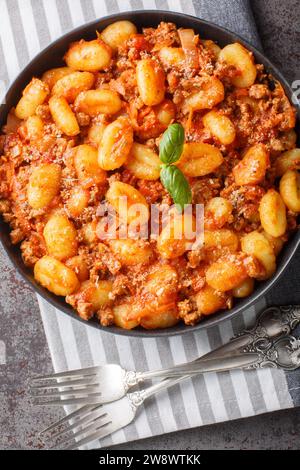 Gnocoques de pommes de terre maison servis avec de la sauce bolognaise à la viande classique en gros plan dans une assiette sur la table. Vue verticale de dessus Banque D'Images