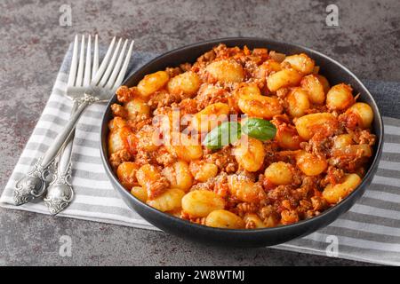 Gnocchi de pommes de terre italiennes cuits avec de la sauce bolognaise à la viande en gros plan dans une assiette sur la table. Horizontal Banque D'Images