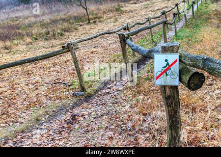 Petit panneau indiquant l'absence de vélo sur le chemin piétonnier entre clôture en bois, plaine d'automne en arrière-plan flou, parc national Hoge Kempen, Lieteberg Zut Banque D'Images