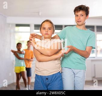 Garçon préadolescent et fille pratiquant Slow foxtrot dans le studio de danse Banque D'Images