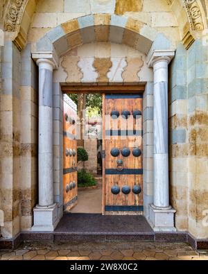 Vue détaillée d'une porte complexe de style mamelouk, y compris la métallurgie dekoratif et les poignées portées par le temps. La porte mène à un passage ombragé Banque D'Images