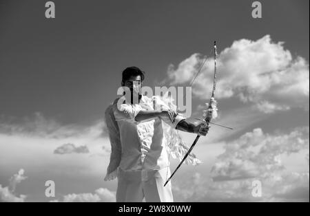 Concept de la Saint-Valentin.Drôle d'ange cupid visant avec l'arc et la flèche sur un fond de ciel dans le ciel. Banque D'Images