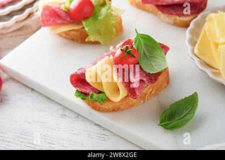 Sandwich au salami. Délicieux sandwichs grillés avec salami en tranches, laitue cheddar et tomates cerise sur fond de marbre blanc. Hommes de restaurant Banque D'Images