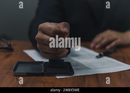 Homme de main estampillant des documents notaire public dans le bureau. Homme d'affaires estampillant l'approbation des documents bancaires de financement du travail ou de marketing d'investissement sur de Banque D'Images