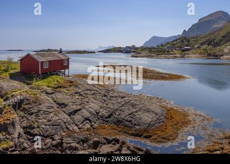 Un rorbu rouge classique, perché sur pilotis sur le rivage lisse, poli à la mer et rocheux de la mer du Nord, offre une vue pittoresque sur Moskenes dans la Lof Banque D'Images