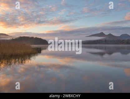 Une aube brumeuse mais belle regardant le long de Derwentwater vers Catbells avec des nuages bas dans les vallées. Banque D'Images