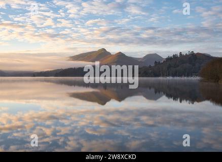 Un matin froid voit des nuages bas dans la vallée autour de la base de Catbells et de la brume sur la surface du lac à Derwentwater. Banque D'Images