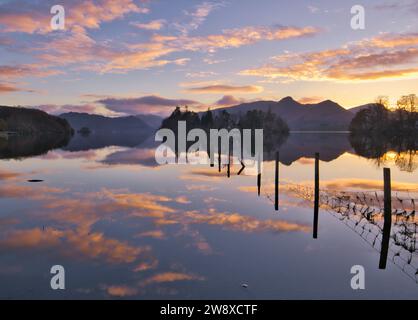 Coucher de soleil reflété dans le lac Derwentwater avec Derwentwater Island et la silhouette distinctive de Catbells fournissant une toile de fond emblématique Banque D'Images