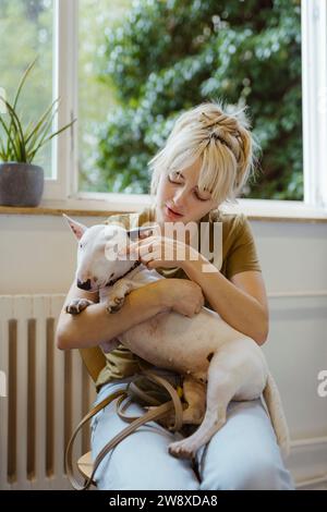 Femme blonde jouant avec Bull terrier en attendant dans la clinique vétérinaire Banque D'Images