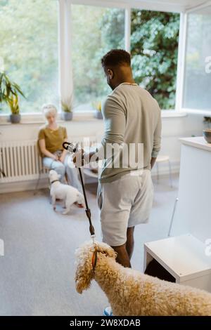 Jeune homme marchant avec chien dans la salle d'attente de la clinique médicale vétérinaire Banque D'Images