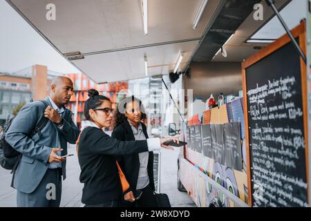 Professionnels d'entreprise hommes et femmes commandant de la nourriture de food truck Banque D'Images