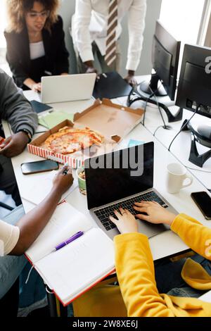 Vue à angle élevé du codage des femmes entrepreneurs sur ordinateur portable lors de la réunion avec des collègues au bureau Banque D'Images