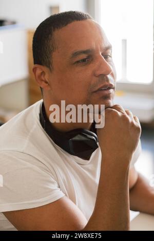Entrepreneur masculin réfléchi avec la main sur le menton au bureau Banque D'Images