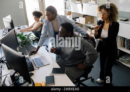 Vue à angle élevé des entrepreneurs masculins et féminins travaillant sur l'ordinateur au bureau dans le bureau Banque D'Images