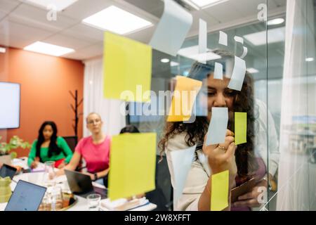 Jeune femme d'affaires menant une séance de brainstorming avec des collègues pendant la réunion au bureau Banque D'Images