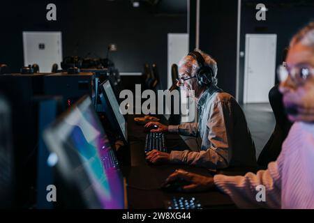Amis féminins et masculins passant du temps libre tout en jouant au jeu vidéo au centre de jeu Banque D'Images