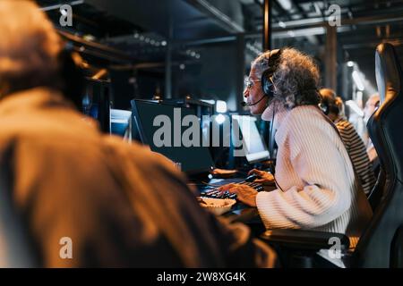 Femmes et hommes âgés jouant à des jeux vidéo sur des ordinateurs au centre de jeux pendant le week-end Banque D'Images