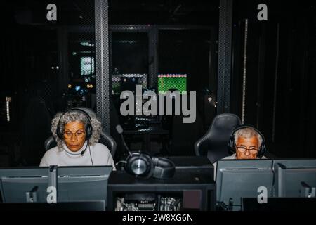 Vieux amis masculins et féminins jouant à des jeux vidéo sur des ordinateurs dans le salon de jeux Banque D'Images
