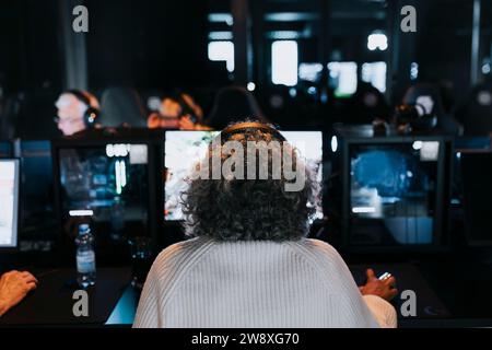 Vue arrière d'une femme âgée jouant au jeu vidéo au centre de jeu Banque D'Images