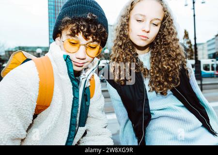 Amis masculins et féminins multiraciaux regardant vers le bas tout en étant assis sur le sentier Banque D'Images