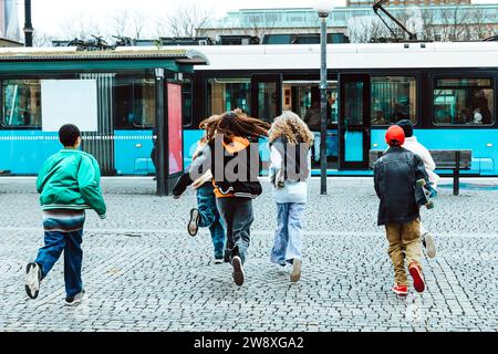 Vue arrière d'amis masculins et féminins courant vers tram en ville Banque D'Images