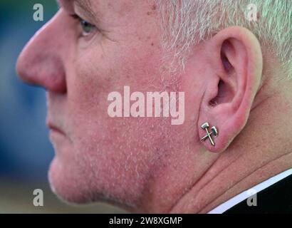 22 décembre 2023, Brandenburg, Jänschwalde : un mineur porte une boucle d'oreille à goujon avec un maillet et du fer, symbole de l'exploitation minière, pour marquer le changement cérémoniel et la fin de l'exploitation du lignite dans la mine à ciel ouvert de Jänschwalde de Lausitz Energie Bergbau AG (LEAG). Après près de 50 ans, l'exploitation régulière de la mine de lignite à ciel ouvert de Jänschwalde, au nord-est de Cottbus, touche à sa fin Les mineurs de l’exploitant de la centrale électrique Leag ont organisé un changement de poste cérémoniel vendredi après-midi pour dire adieu. Le lignite est extrait dans la mine à ciel ouvert depuis 1976. Les zones seront recyclées dans Th Banque D'Images