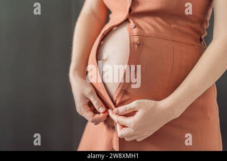 Pas besoin de lutter avec la fixation. Choisissez une robe de maternité qui apporte confort et style à votre ventre enceinte Banque D'Images