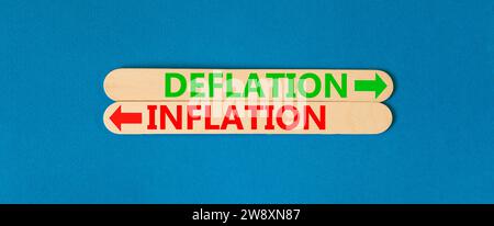 Symbole de déflation et d'inflation. Concept Word déflation inflation sur beau bâton en bois. Belle table bleue fond bleu. Déflation ou in Banque D'Images