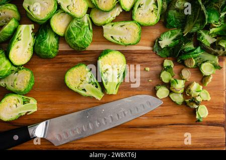 Halved Brussels Sprout vu Close Up sur une planche à découper en bois : Fresh brussels Sprout divisé en deux avec un couteau santoku sur une planche à découper en bois Banque D'Images
