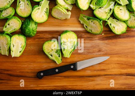 Halved Brussels Sprout vu Close Up on a Wood Cut Board : Fresh brussels Sprouts divisé en deux avec un couteau d'épluchage sur une planche à découper en bois Banque D'Images