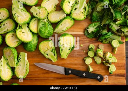 Halved Brussels Sprout vu Close Up on a Wood Cut Board : Fresh brussels Sprouts divisé en deux avec un couteau d'épluchage sur une planche à découper en bois Banque D'Images
