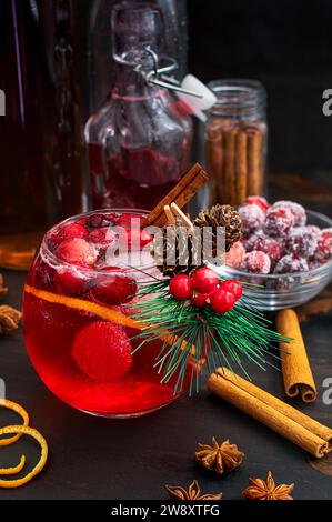 Canneberge épicée Bourbon Old Fashioned avec canneberges sucrées : cocktail rouge bourbon de Noël décoré d'une petite branche à feuilles persistantes Banque D'Images
