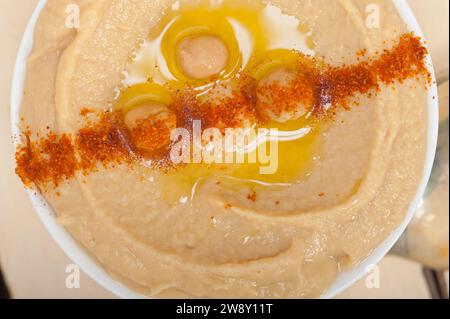 Houmous traditionnels de pois chiches avec de l'huile d'olive à la menthe et du paprika sur le dessus, photographie alimentaire Banque D'Images