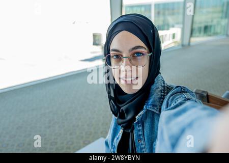 jeune femme prenant selfie à l'aéroport avec l'avion en arrière-plan Banque D'Images