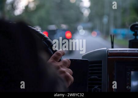 mains de vieil homme tout en conduisant sur la route avec des lumières floues et la circulation des voitures Banque D'Images