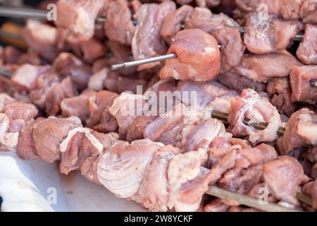 Les morceaux de viande crue sont prêts à être grillés sur le feu et enfilés sur des brochettes métalliques Banque D'Images