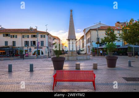 Saint Maximin, France - 1 octobre 2023 : banc rouge sur la place de Saint Maximin la Sainte Baume. Heure du coucher du soleil. Banque D'Images