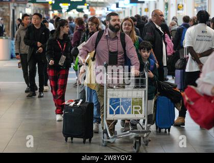 Richmond, Canada. 22 décembre 2023. Des voyageurs sont vus à l'aéroport international de Vancouver à Richmond, Colombie-Britannique, Canada, le 22 décembre 2023. Le vendredi a été marqué comme le jour de voyage le plus achalandé de la saison des fêtes, selon l’Administration de l’aéroport international de Vancouver. Crédit : Liang Sen/Xinhua/Alamy Live News Banque D'Images