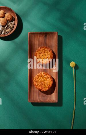 Sur fond vert avec ombre de fenêtre, deux plateaux en bois de gâteaux de lune et noix décorés. Concept de festival chinois de mi-automne fabriqué à partir de Mo Banque D'Images