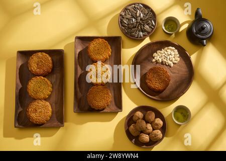 Simplicité minimale disposition des mooncakes sur fond jaune pour le Festival de la mi-automne. Sur des plateaux en bois remplis de gâteaux de lune appétissants, de graines sèches et de set Banque D'Images