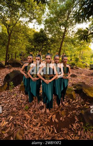 Un grand plan d'une femme asiatique debout ensemble dans la forêt tout en portant un costume de danse verte avec des feuilles mortes en arrière-plan Banque D'Images