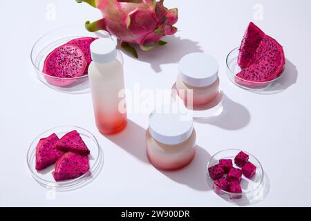 Concept minimal pour la publicité des cosmétiques avec des ingrédients naturels populaires - tranches de fruit du dragon rouge dans une boîte de Pétri avec une bouteille et des pots non étiquetés Banque D'Images