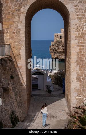 Femme marche aqueduc de trouée dans la vieille ville de Polignano a Mare ville Banque D'Images