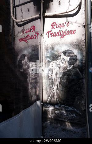 Graffiti d'un homme mangeant des spaghettis avec ses mains devant un restaurant traditionnel dans l'une des banlieues les plus pauvres de Naples. Banque D'Images