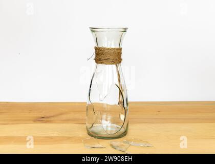 Bouteille en verre cassée sur une table en bois Banque D'Images