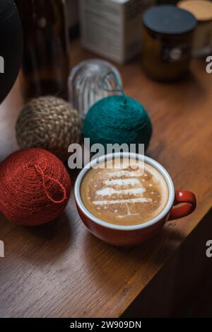 Tasse à café rouge avec latte art de pin sur table en bois rustique Banque D'Images
